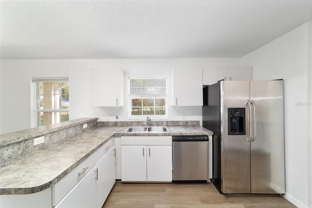 5596 NW 57th St, Ocala, FL 34482 - kitchen with stainless steel appliances, a peninsula, white cabinetry, light wood-style flooring, and healthy amount of natural light