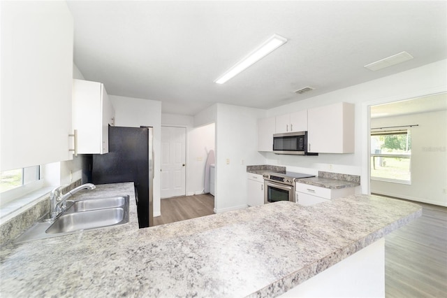 5596 NW 57th St, Ocala, FL 34482 - kitchen with appliances with stainless steel finishes, light wood-style floors, white cabinetry, light countertops, and a peninsula