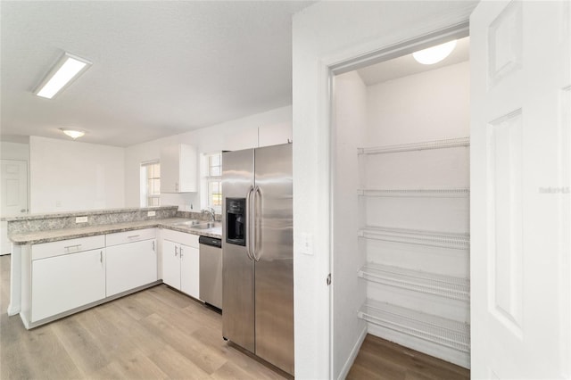 5596 NW 57th St, Ocala, FL 34482 - kitchen featuring appliances with stainless steel finishes, white cabinets, light wood-style floors, light countertops, and a peninsula
