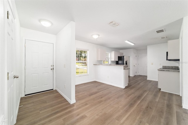 5596 NW 57th St, Ocala, FL 34482 - kitchen featuring stainless steel fridge with ice dispenser, wood finished floors, white cabinets, and a peninsula