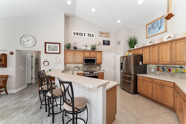 19115 SW 98th Loop, Dunnellon, FL 34432 - kitchen with stainless steel appliances, high vaulted ceiling, a kitchen bar, decorative backsplash, and light countertops