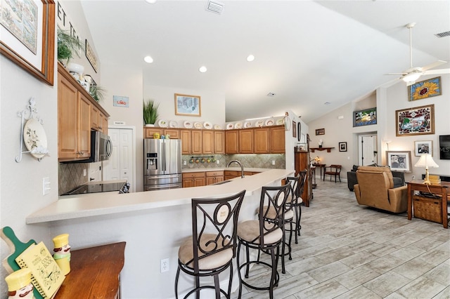 19115 SW 98th Loop, Dunnellon, FL 34432 - kitchen featuring stainless steel appliances, high vaulted ceiling, backsplash, light countertops, and a kitchen breakfast bar