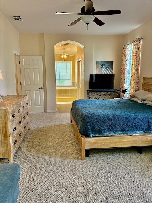 19480 SW 100th Loop, Dunnellon, FL 34432 - bedroom featuring arched walkways, light colored carpet, ceiling fan, and ensuite bath