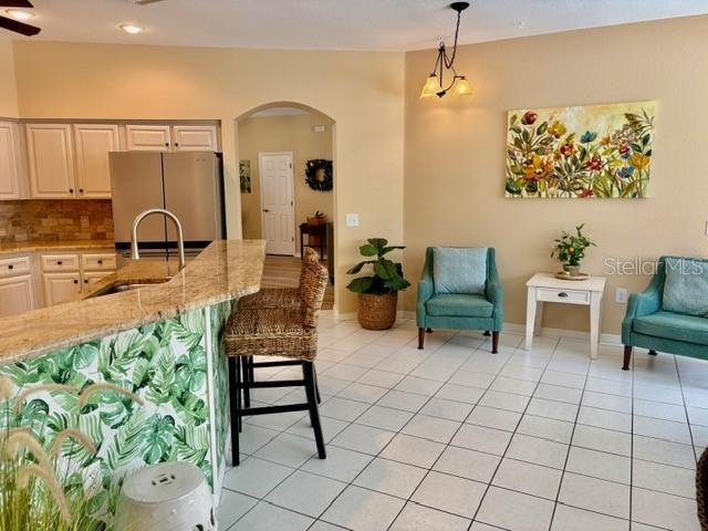 19480 SW 100th Loop, Dunnellon, FL 34432 - kitchen with freestanding refrigerator, arched walkways, open floor plan, decorative light fixtures, and light tile patterned floors