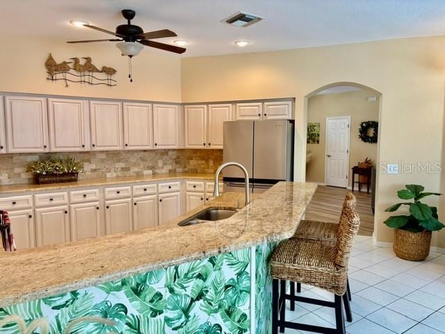 19480 SW 100th Loop, Dunnellon, FL 34432 - kitchen with freestanding refrigerator, arched walkways, light stone countertops, and decorative backsplash