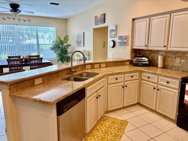 19480 SW 100th Loop, Dunnellon, FL 34432 - kitchen featuring stainless steel dishwasher, a peninsula, light tile patterned floors, a ceiling fan, and light stone countertops