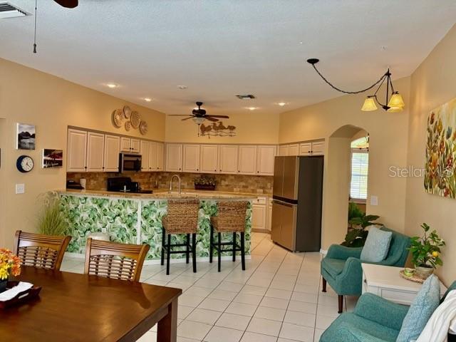 19480 SW 100th Loop, Dunnellon, FL 34432 - kitchen with freestanding refrigerator, a ceiling fan, light tile patterned flooring, and decorative backsplash