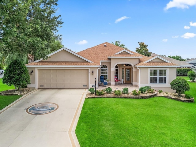 2721 Day Lily Run, The Villages, FL 32162 - mediterranean / spanish-style house with stucco siding, a front yard, concrete driveway, a garage, and roof with shingles