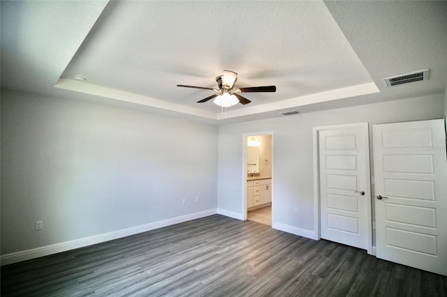 9 Hemlock Terrace Ln, Ocala, FL 34472 - unfurnished bedroom with a tray ceiling, dark wood-type flooring, ensuite bathroom, a closet, and a ceiling fan