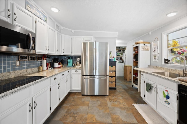 581 NE 44th Ave, Ocala, FL 34470 - kitchen featuring stainless steel appliances, backsplash, white cabinets, washer / clothes dryer, and stone finish floors
