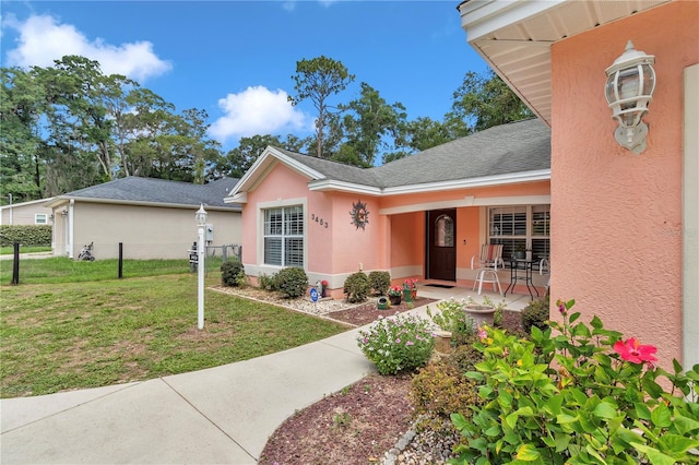 3453 SE 147th Ln, Summerfield, FL 34491 - view of front of house with a front yard, stucco siding, covered porch, and a shingled roof