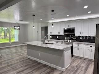 1467 E Odin Dr, Citrus Springs, FL 34434 - kitchen featuring stainless steel appliances, tasteful backsplash, an island with sink, wood finished floors, and hanging light fixtures