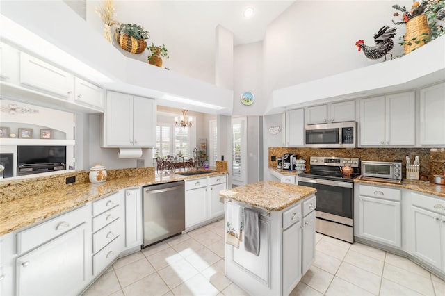 3629 SE 54th Ave, Ocala, FL 34480 - kitchen featuring stainless steel appliances, a towering ceiling, a chandelier, light tile patterned floors, and tasteful backsplash