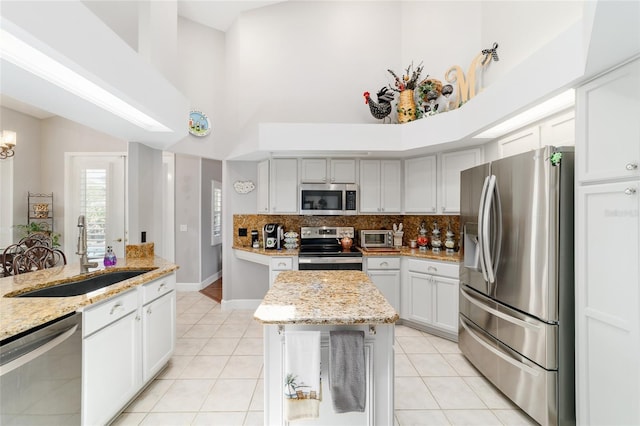3629 SE 54th Ave, Ocala, FL 34480 - kitchen featuring stainless steel appliances, a towering ceiling, light tile patterned flooring, decorative backsplash, and a center island