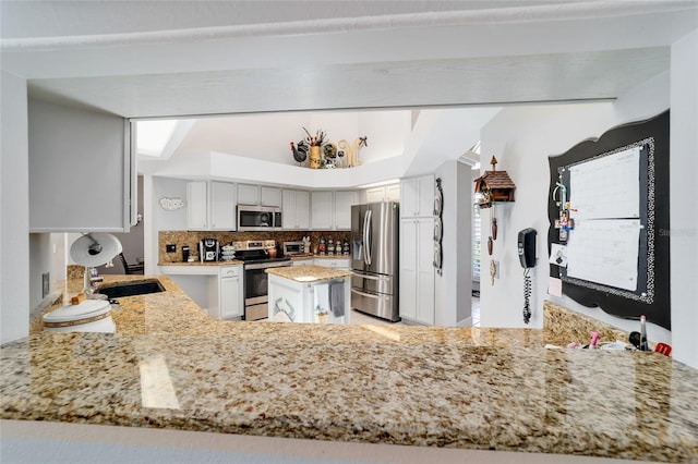 3629 SE 54th Ave, Ocala, FL 34480 - kitchen with stainless steel appliances, backsplash, light stone counters, white cabinetry, and a peninsula