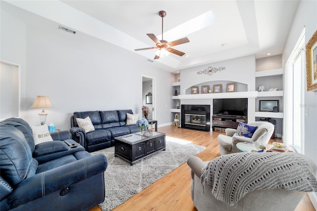 3629 SE 54th Ave, Ocala, FL 34480 - living area featuring light wood-style floors, built in shelves, a ceiling fan, a raised ceiling, and a fireplace with flush hearth