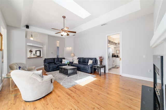 3629 SE 54th Ave, Ocala, FL 34480 - living area with a raised ceiling, ceiling fan, a skylight, light wood-style floors, and a fireplace with flush hearth