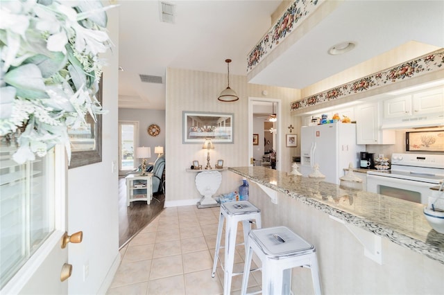 3629 SE 54th Ave, Ocala, FL 34480 - kitchen with white appliances, under cabinet range hood, light stone countertops, light tile patterned floors, and white cabinets