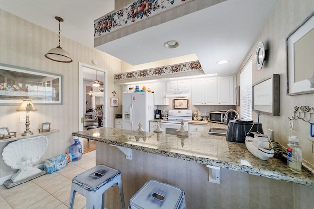 3629 SE 54th Ave, Ocala, FL 34480 - kitchen featuring white appliances, a peninsula, under cabinet range hood, light stone countertops, and a breakfast bar area