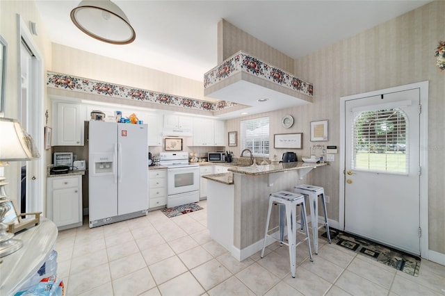 3629 SE 54th Ave, Ocala, FL 34480 - kitchen with white appliances, a peninsula, wallpapered walls, white cabinetry, and a breakfast bar area