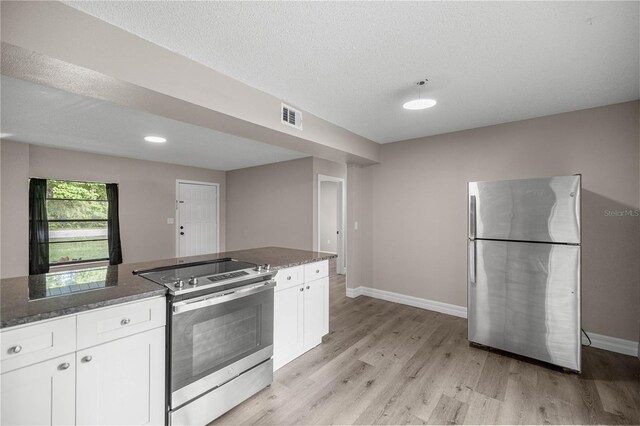 6021 NW 54th Ter, Ocala, FL 34482 - kitchen featuring appliances with stainless steel finishes, white cabinetry, light wood-style flooring, dark stone countertops, and a textured ceiling