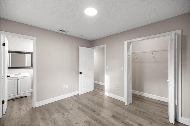 6021 NW 54th Ter, Ocala, FL 34482 - unfurnished bedroom featuring light wood-type flooring, connected bathroom, a textured ceiling, and a closet