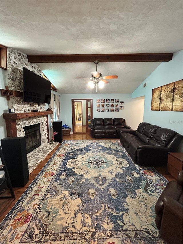 2070 SE 50th Ter, Ocala, FL 34480 - living room with wood finished floors, a stone fireplace, a ceiling fan, and a textured ceiling