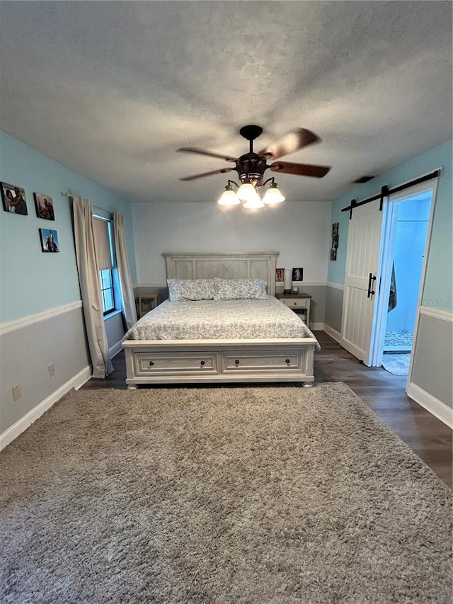 2070 SE 50th Ter, Ocala, FL 34480 - bedroom with a textured ceiling, a barn door, a ceiling fan, and dark wood-style floors