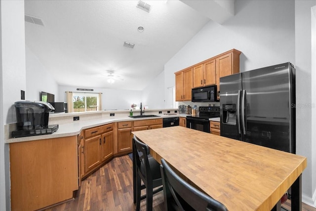 3946 SW 133rd Loop, Ocala, FL 34473 - kitchen featuring black appliances, a peninsula, vaulted ceiling, light countertops, and dark wood-type flooring