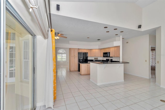 5210 Camberlea Ave, Zephyrhills, FL 33541 - kitchen with light brown cabinetry, black appliances, light tile patterned flooring, dark countertops, and a kitchen breakfast bar