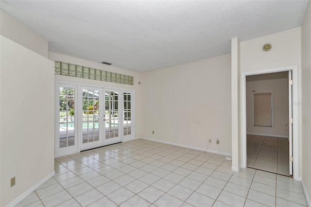 5210 Camberlea Ave, Zephyrhills, FL 33541 - spare room featuring french doors, a textured ceiling, light tile patterned floors, and a smoke detector