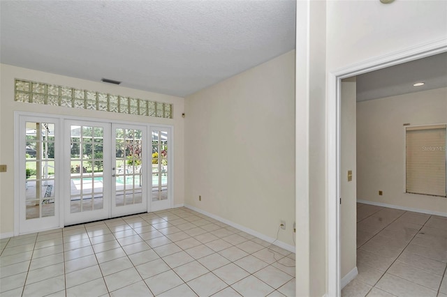 5210 Camberlea Ave, Zephyrhills, FL 33541 - empty room featuring french doors, light tile patterned flooring, and a textured ceiling