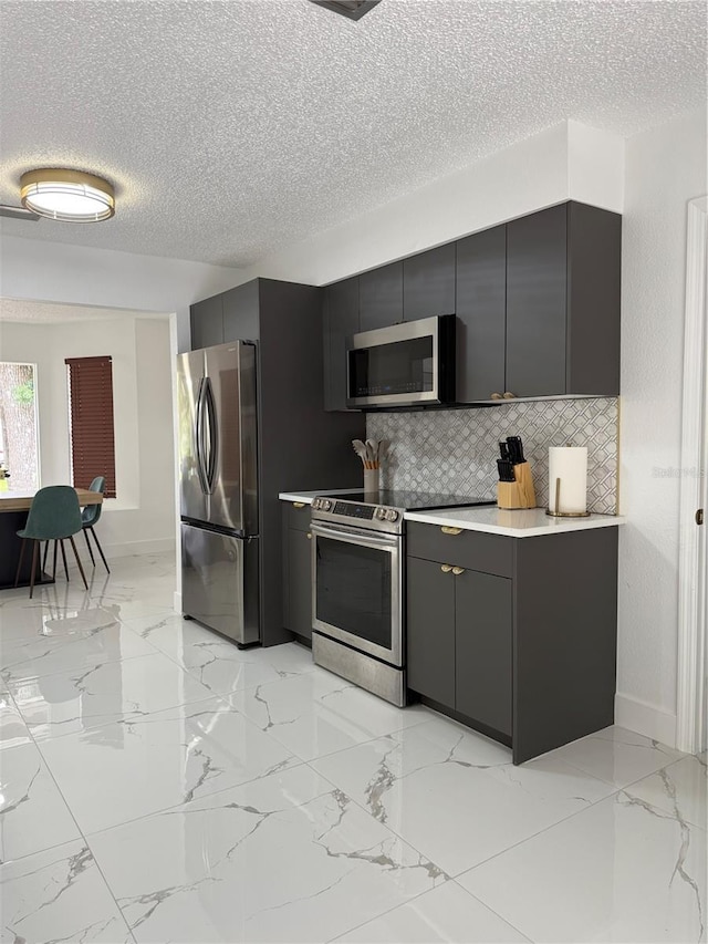 3585 N Hiawatha Ter, Crystal River, FL 34428 - kitchen featuring appliances with stainless steel finishes, gray cabinets, a textured ceiling, decorative backsplash, and light marble finish flooring