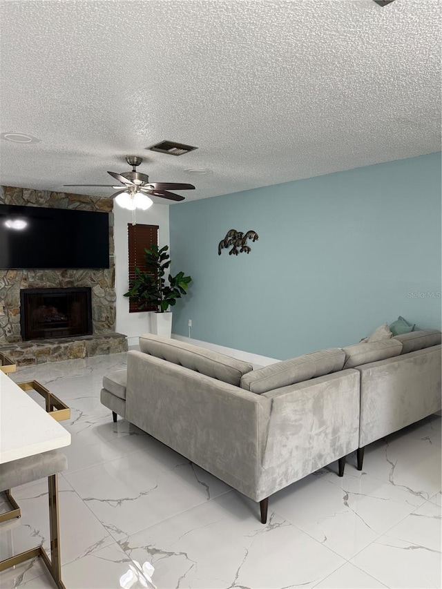 3585 N Hiawatha Ter, Crystal River, FL 34428 - living room with marble finish floors, a textured ceiling, a ceiling fan, and a fireplace