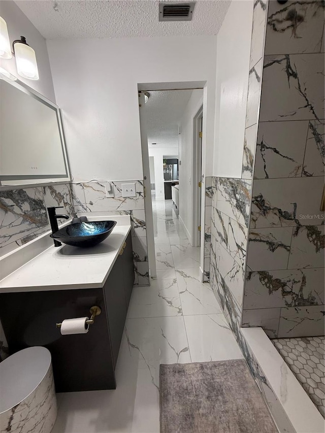 3585 N Hiawatha Ter, Crystal River, FL 34428 - full bath featuring tile walls, vanity, a tile shower, a textured ceiling, and wainscoting