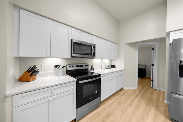 3520 NW 46th Ter, Gainesville, FL 32606 - kitchen with stainless steel appliances, white cabinetry, light wood-style flooring, and light stone counters