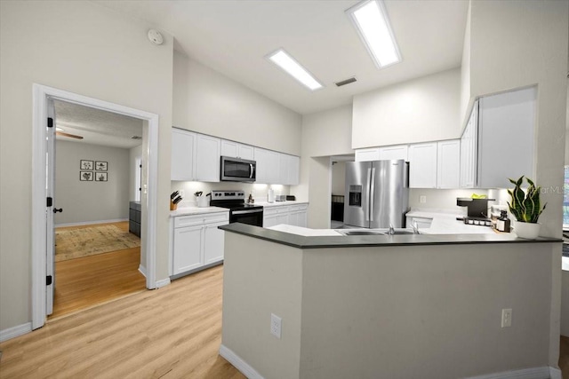 3520 NW 46th Ter, Gainesville, FL 32606 - kitchen with appliances with stainless steel finishes, high vaulted ceiling, light wood-type flooring, a peninsula, and white cabinets