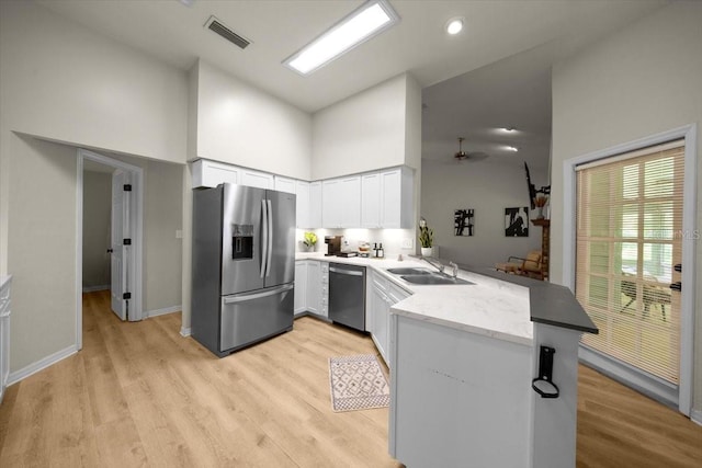 3520 NW 46th Ter, Gainesville, FL 32606 - kitchen with stainless steel appliances, high vaulted ceiling, a peninsula, and light wood-style flooring