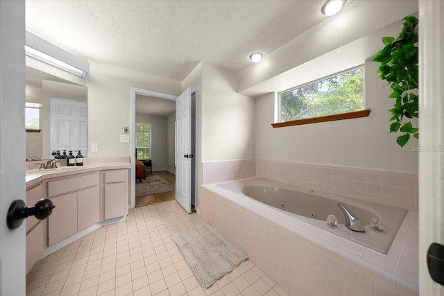 3520 NW 46th Ter, Gainesville, FL 32606 - ensuite bathroom featuring a tub with jets, tile patterned floors, vanity, healthy amount of natural light, and a textured ceiling