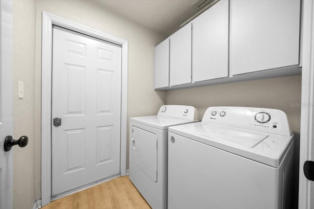 3520 NW 46th Ter, Gainesville, FL 32606 - laundry area featuring washing machine and dryer, cabinet space, and light wood finished floors