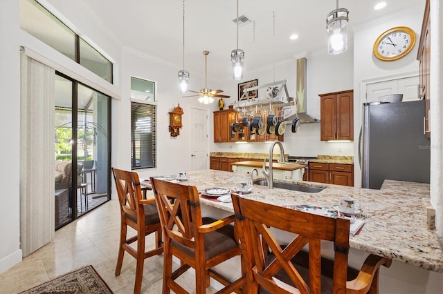 5233 Fountain Walk, Lady Lake, FL 32159 - kitchen with freestanding refrigerator, crown molding, brown cabinetry, a kitchen breakfast bar, and a peninsula