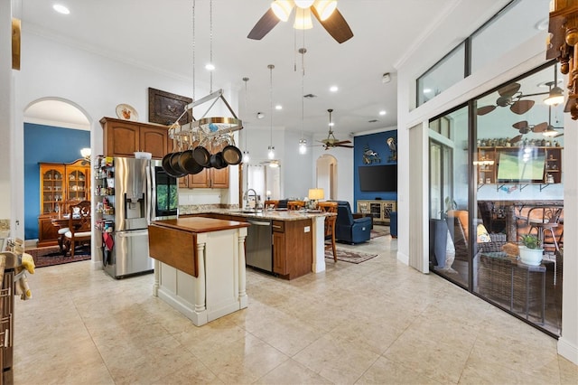 5233 Fountain Walk, Lady Lake, FL 32159 - kitchen with stainless steel appliances, a ceiling fan, arched walkways, a center island, and crown molding