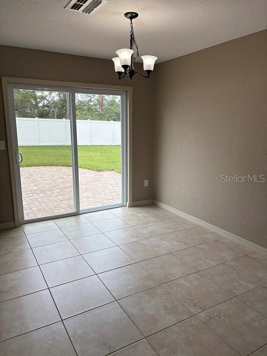 2494 SW 170th Loop, Ocala, FL 34473 - spare room featuring healthy amount of natural light, a chandelier, light tile patterned floors, and a textured wall