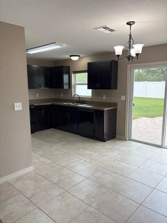 2494 SW 170th Loop, Ocala, FL 34473 - kitchen with black dishwasher, dark cabinets, a textured ceiling, light tile patterned flooring, and a chandelier