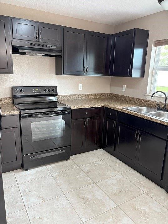 2494 SW 170th Loop, Ocala, FL 34473 - kitchen with black electric range, under cabinet range hood, and light tile patterned flooring