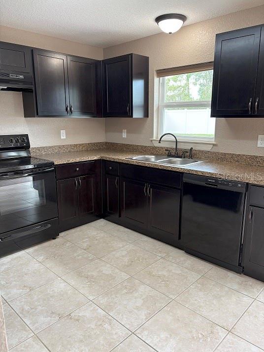 2494 SW 170th Loop, Ocala, FL 34473 - kitchen with black appliances, ventilation hood, a textured ceiling, a textured wall, and dark cabinetry