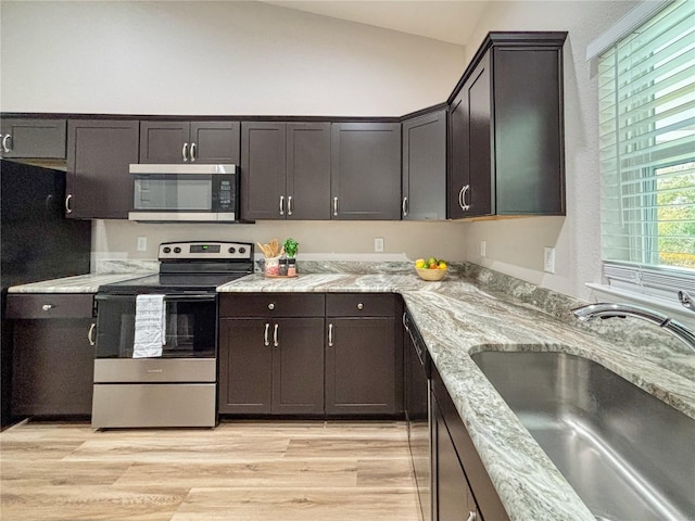 6431 SW 145th Lane Rd, Ocala, FL 34473 - kitchen featuring stainless steel appliances, lofted ceiling, light wood-style flooring, light stone counters, and dark brown cabinetry