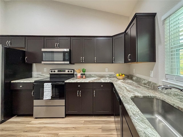 6431 SW 145th Lane Rd, Ocala, FL 34473 - kitchen featuring stainless steel appliances, vaulted ceiling, light wood finished floors, light stone counters, and dark brown cabinetry