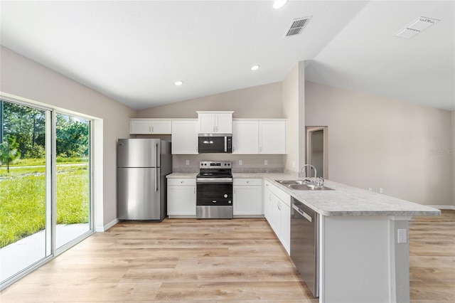 2869 SE 142nd Pl, Summerfield, FL 34491 - kitchen with stainless steel appliances, light countertops, a peninsula, lofted ceiling, and light wood-style floors