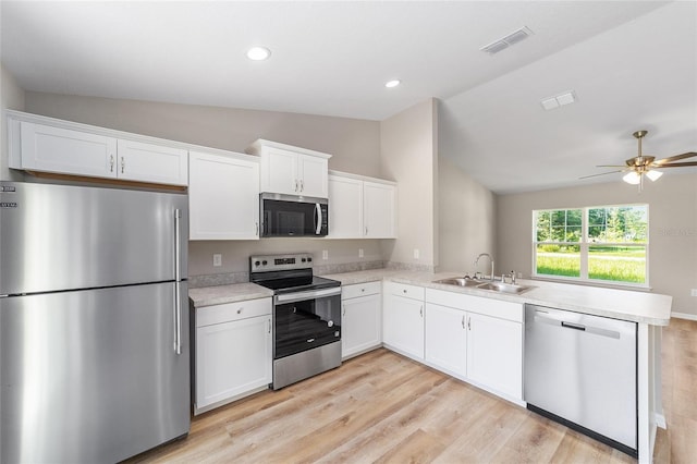 2869 SE 142nd Pl, Summerfield, FL 34491 - kitchen featuring appliances with stainless steel finishes, vaulted ceiling, a peninsula, light wood finished floors, and light countertops